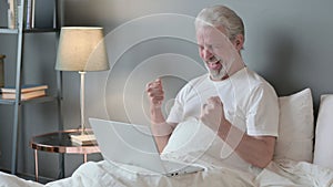 Successful Senior Old Man with Laptop Celebrating in Bed