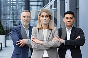 Successful and serious diverse team of three business people, focused looking at camera