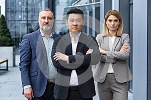 Successful and serious diverse team of three business people, focused looking at camera