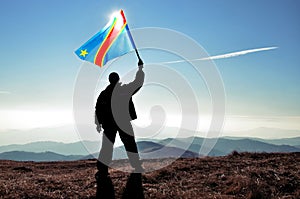 Successful silhouette man winner waving Democratic Republic of Congo flag on top of the mountain