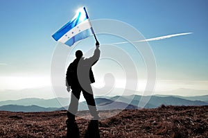 Successful silhouette man winner waving Honduras flag on top of the mountain