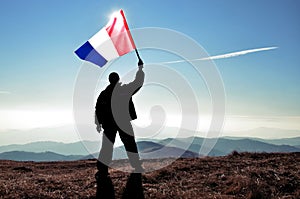 Successful silhouette man winner waving Mayotte flag on top of the mountain