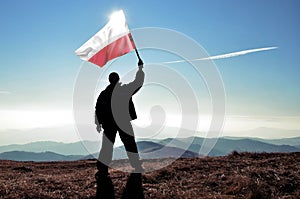Successful silhouette man winner waving Poland flag on top of the mountain