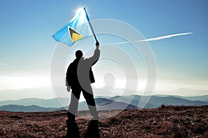 Successful silhouette man winner waving Saint Lucia flag on top of the mountain