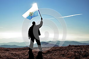 Successful silhouette man winner waving San Marino flag on top of the mountain