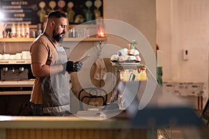 Successful small business owner in cafe using digital tablet and looking at screen. Serious barista with a beard