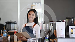 Successful small business owner smiling and standing behind the counter in the coffee shop.