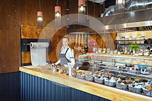 Successful small business owner woman standing behind counter of newly opened restaurant