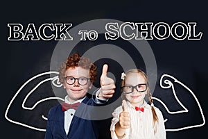 Successful smart kids in school uniform having fun on blackboard background, back to school and brain power concept