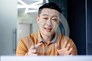 Successful smiling asian businessman talking to colleagues remotely, man using laptop for video call, joyful worker in