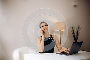 Successful smiling business woman at work consulting on phone, sitting at her working place in office, copy space.