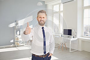 Successful smiling businessman raised his thumb up while standing in a white office.