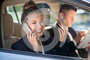 Successful smiling woman talking on a smartphone in a car