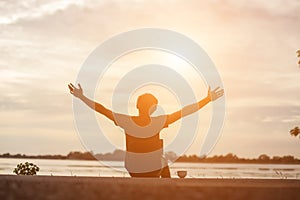 Successful sportsman raising arms on golden sky back lighting sunset summer after cross running. Fitness male athlete with arms up