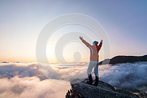 Successful sporty girl is standing at the edge of the precipice. Mountains landscape in the foggy morning. Sunrise. Autumn photo