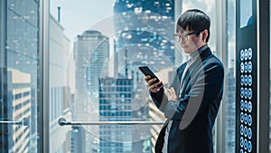 Successful Stylish Japanese Businessman Riding Glass Elevator to Office in Modern Business Center.