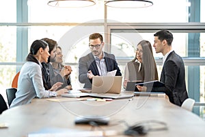 Successful team leader and business executive leading a staff meeting in office.