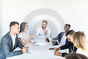 Successful team leader and business owner leading informal in-house business meeting. Businessman working on laptop in foreground