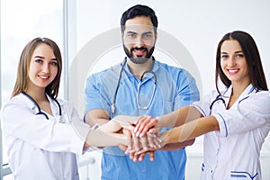 Successful team of medical doctors are looking at camera and smiling while standing in hospital