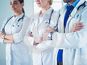 Successful team of medical doctors are looking at camera and smiling while standing in hospital