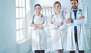 Successful team of medical doctors are looking at camera and smiling while standing in hospital