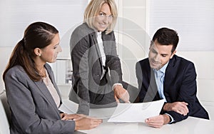 Successful teamwork: career businesswoman and businessman sitting around a table talking together in a meeting.