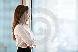 Successful thoughtful woman business leader looking out of big w
