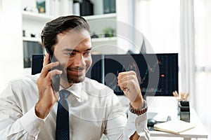 Successful trader businessman raising fist up, calling on phone. Surmise.