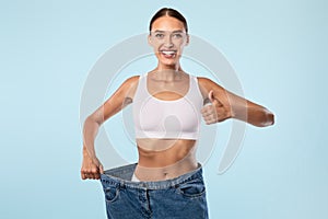 Woman Pulling Her Old Large Loose Jeans Showing Thumbs Up