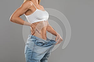 Successful Weight Loss. Young Woman Wearing Oversized Jeans After Effective Diet