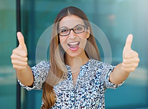 Successful winning young business woman with thumbs up outdoors