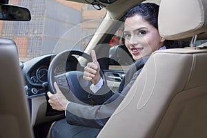 Successful woman in car with thumb up