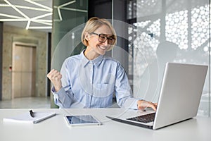 Successful woman celebrating victory and great achievement results at workplace, blonde business woman inside office