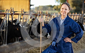 Successful woman farmer standing in cowshed at dairy cow farm