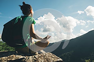 woman hiker meditation on mountain top cliff edge photo