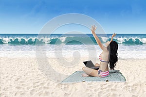 Successful woman working with laptop at beach