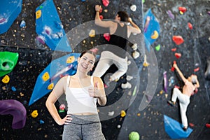 after successful workout, young female sportswoman poses near bouldering wall