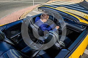 Successful yang businessman in yellow cabrio car.