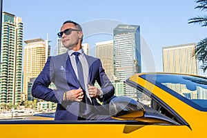 Successful yang businessman in yellow cabrio car.