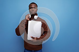 successful young african man businessman with laptop and headphones on background with copy space