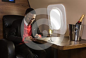 Successful young Afro American black businessman sitting in the chair of his private jet