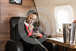 Successful young Afro American black businessman sitting in the chair of his private jet