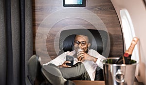 Successful young Afro American black businessman sitting in the chair of his private jet