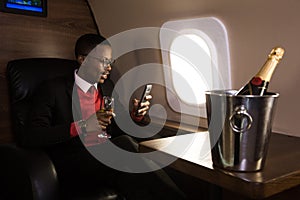 Successful young Afro American black businessman sitting in the chair of his private jet