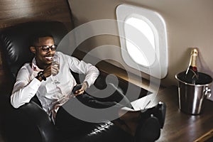 Successful young Afro American black businessman sitting in the chair of his private jet