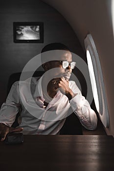 Successful young Afro American black businessman sitting in the chair of his private jet