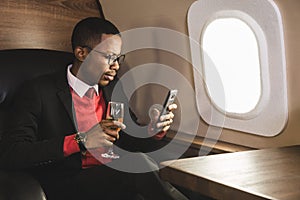 Successful young Afro American black businessman sitting in the chair of his private jet