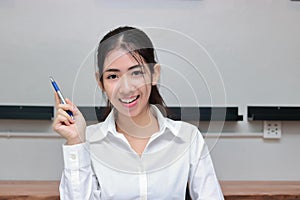 Successful young Asian business woman with pen having idea in workplace.