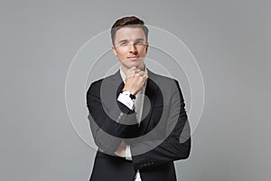 Successful young business man in classic black suit shirt posing isolated on grey background studio portrait