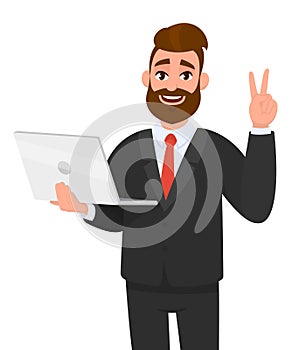 Successful young business man holding/showing a latest brand new laptop computer and doing, making, showing V, victory, peace.